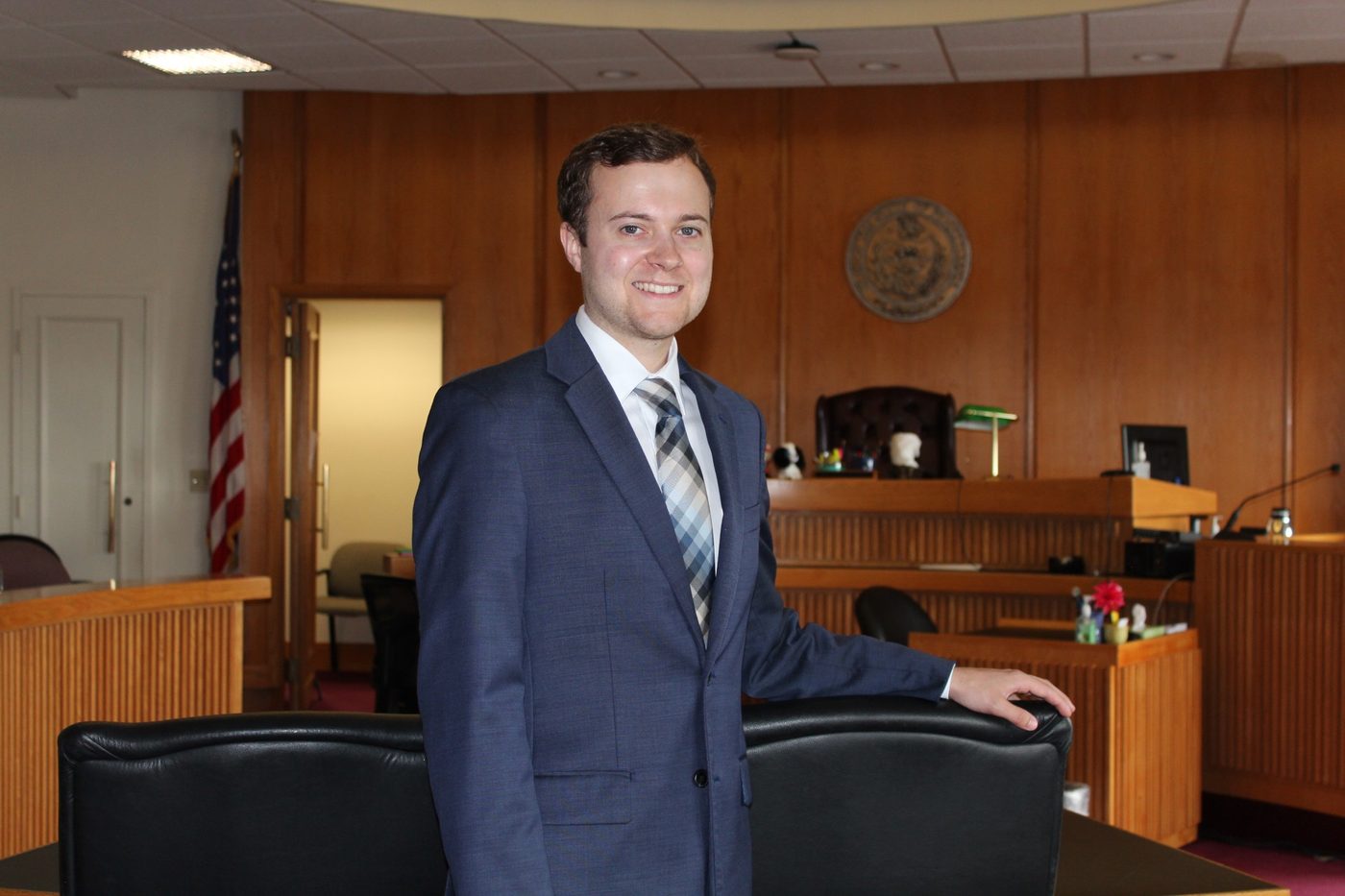 Jordan Rhone, Esq. standing in a courtroom in a navy suit